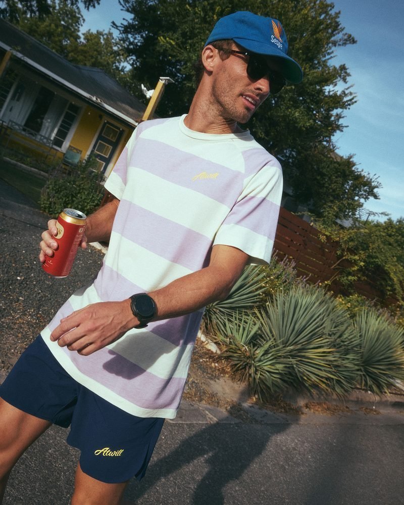 Runner in the Ellis Tee and navy East End Shorts with a drink on an Austin street